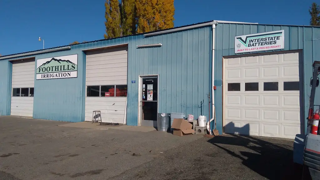 Front of the Foothills Irrigation store: roll-up doors, the mountain sign and the gravel lot