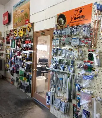 Pegboard wall of irrigation fittings and repair parts beside a SharkBite display and a Toro sign