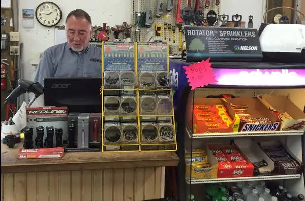 A Foothills Irrigation salesman at the till beside a Rotator sprinkler display and parts bins